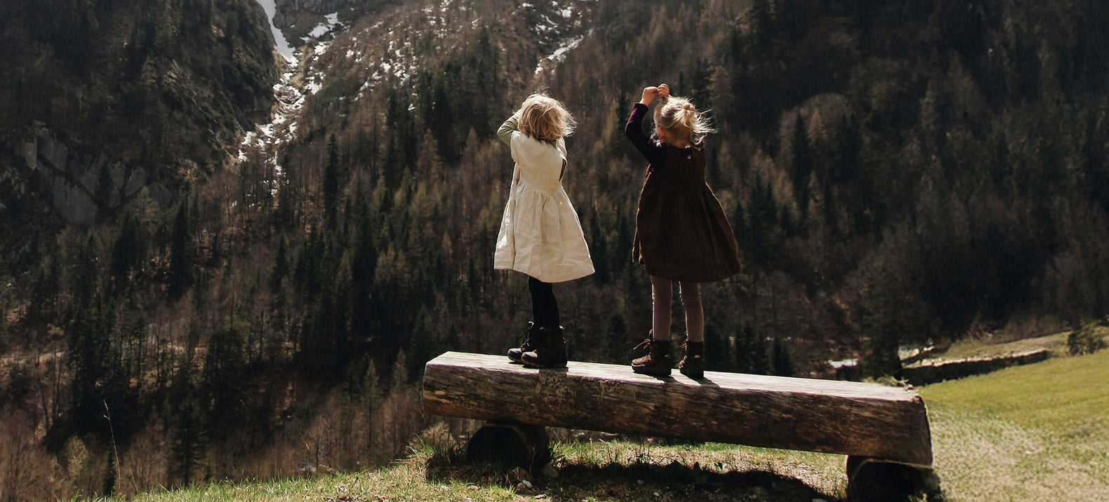 Zwei Mädchen auf einer Holzbank in den Bergen