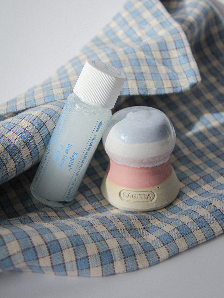 Sagitta Hautschrubbel in der Farbe Zuckerwatte mit rosa/blau/weißen Streifen und Urea Serum bei Hornhaut und trockenen Füßen 